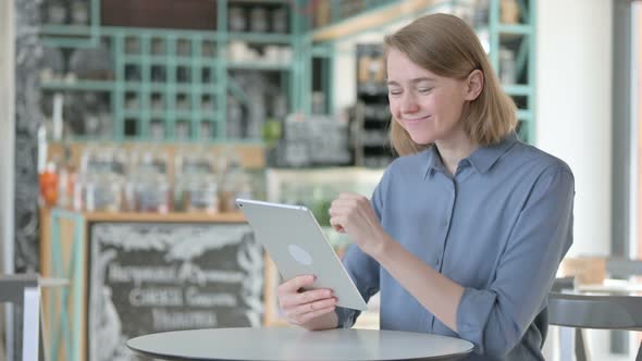 Successful Young Woman Celebrating on Tablet in Cafe