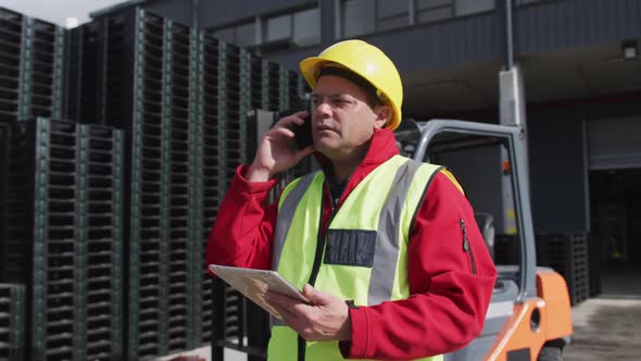 Warehouse worker talking on phone outside factory