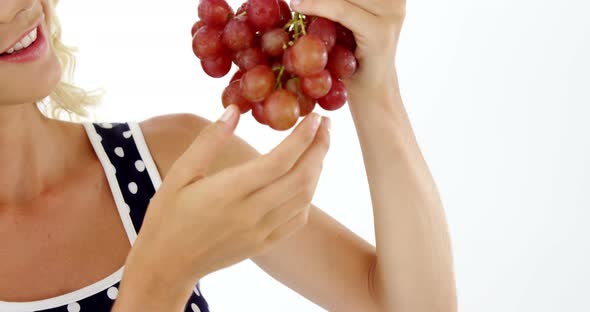 Beautiful woman looking at bunch of red grapes