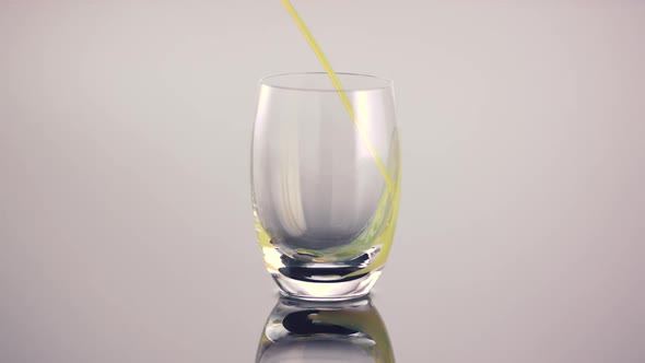 Orange juice pouring into a glass from bottle pourer in slow motion