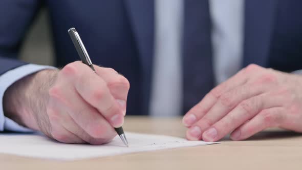 Hands Close Up of Middle Aged Businessman Writing on Paper