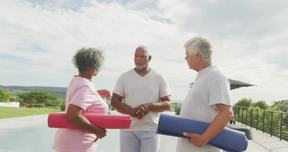 Happy senior diverse people practicing yoga in garden at retirement home