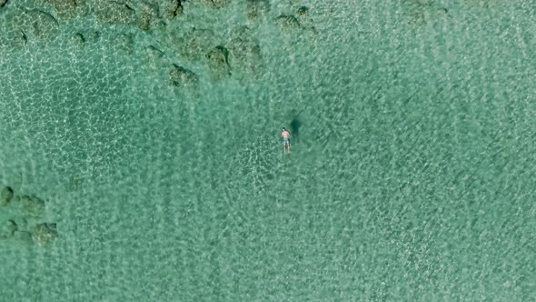 Lonely person scuba diving near coastline of Crete island, aerial top down ascending view