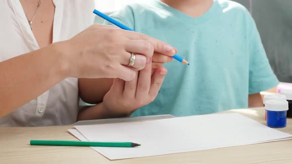 Mother Teaching Her Boy Son Holding Pencil and Drawing or Writing