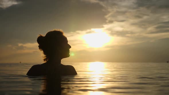 Silhouette Of Woman Swimming In The Sea At Sunset