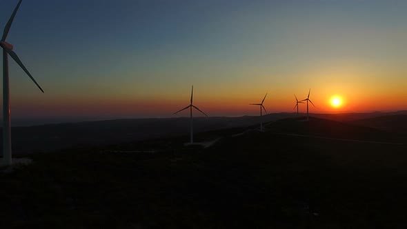 Sun setting behind elegant windmills on a hill