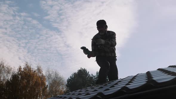 Roofer with Two Screwdrivers Walking on a Metal Roof Without Insurance