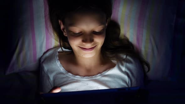 Girl Lying in Bed and Watching Video on Tablet