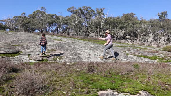 A bushman and his son walk accross granite mountains in Australias bush.