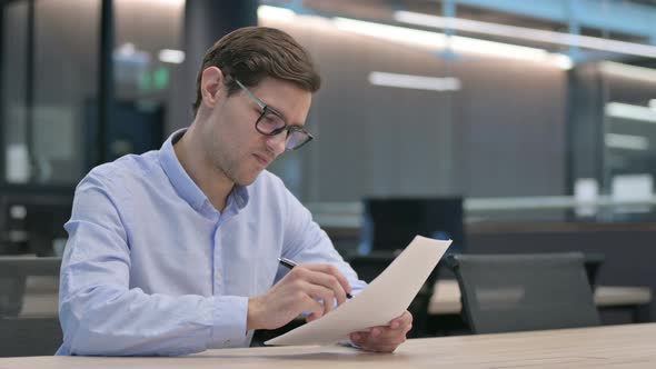 Young Man Reacting to Loss While Reading Documents