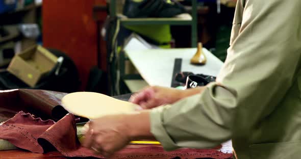 Cobbler cutting a piece of leather