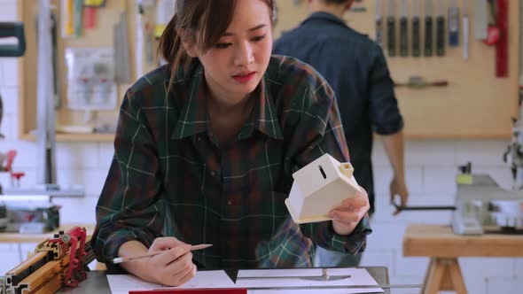 Asian female carpenter creating and drawing new wooden project