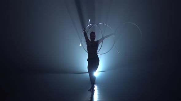 Gymnast in the Air Twists Hoops with Her Hands