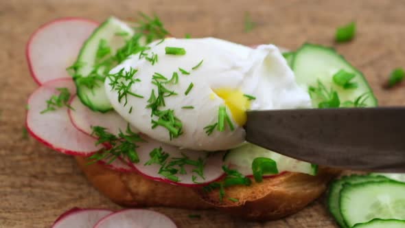 hand with a knife cuts a chicken poached egg 