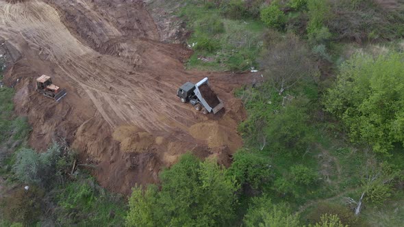 Aerial shot: tipper pouring out soil on place preparing for construction residential house.