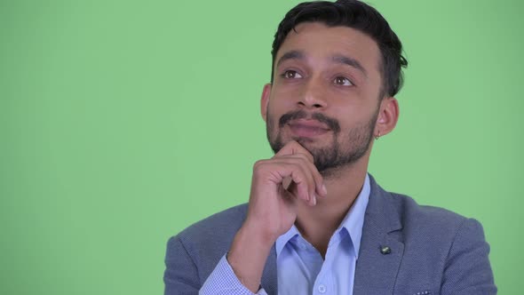 Face of Happy Young Bearded Persian Businessman Thinking and Looking Up