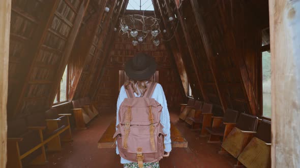 Stylish Tourist Woman in Hat with Backpack Coming in Old Vintage Style Wooden Hut