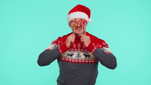 Funny Man in Red New Year Sweater Holding Candy Striped Lollipops Hiding Behind Them Fooling Around