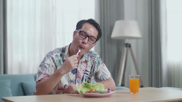 Asian Man Eating Healthy Food Before Smiling And Showing Thumbs Up Gesture To Camera At Home