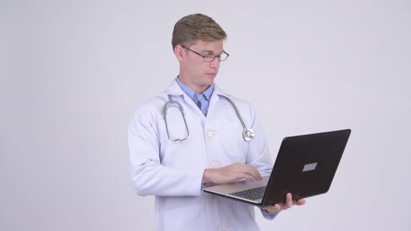Happy Young Handsome Man Doctor Thinking While Using Laptop