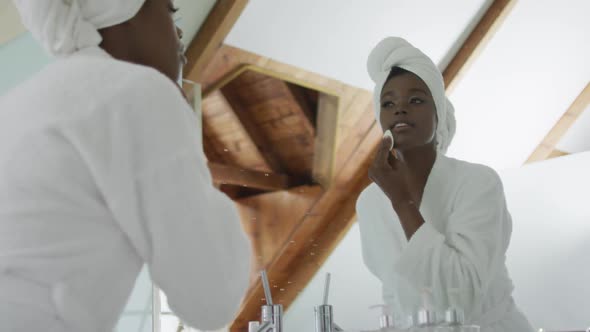 African american attractive woman removing make up in bathroom