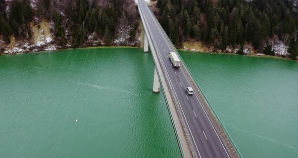 Quadcopter Video of a Bridge Across a River to Hills Covered in Snowy Forest