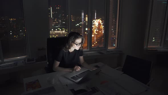 Manager Works Until Late in the Office. Young Female Entrepreneur Working on a Laptop Late at Night