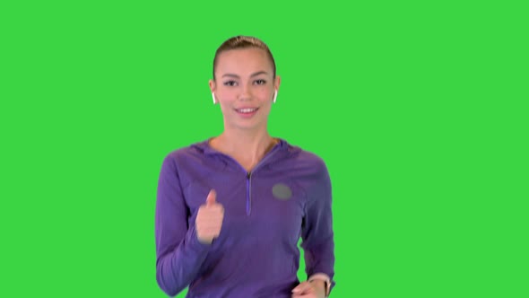 Female Runner Athlete Running and Listening Music in Wireless Ear Buds on a Green Screen Chroma Key