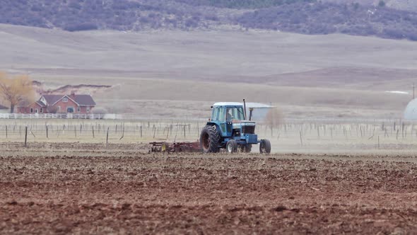 Farmer driving tractor through field plowing through the soil