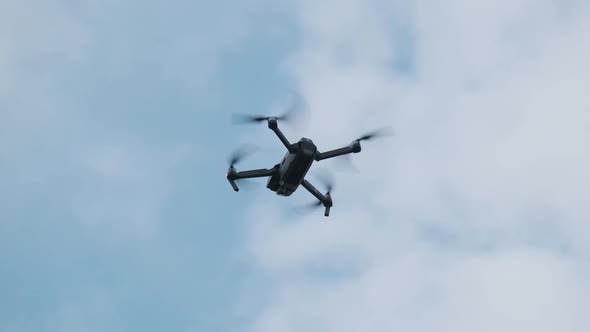 Drone Hangs in the Air Against the Blue Sky, View From Below. Slow Motion