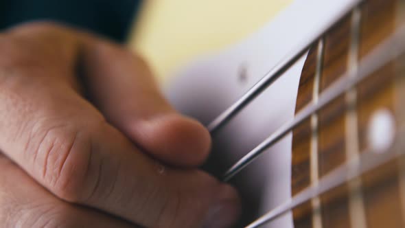 Musician Plays White Bass Guitar with Metal Strings Closeup