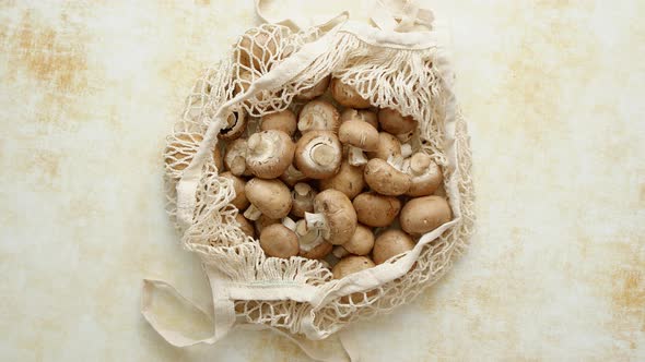 Young Fresh Champignons in a Ecological Zero-waste Net Bag Placed on Beige Background