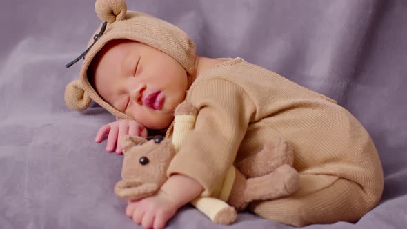 happy newborn baby weaing cute Mouse costume lying sleeps and hug doll on Beige background