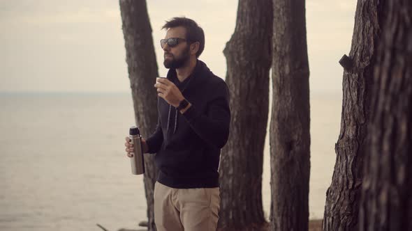 Man Relaxing On City Beach And Drinks Hot Chocolate. Taking Break On Road Trip. Tourist Man.