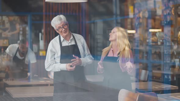 View Through Window of Mature Couple Cafe Owners Discussing Business Development