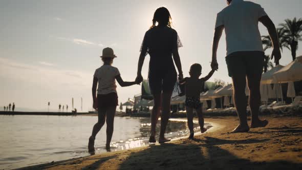 Happy Young Family Have Fun Walking on Beach at Sunset. Family Silhouette Travel Holiday.