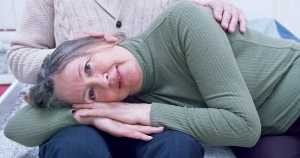 Portrait of an Elderly Woman Who Lies on Her Husband's Lap and Looks Into the Camera