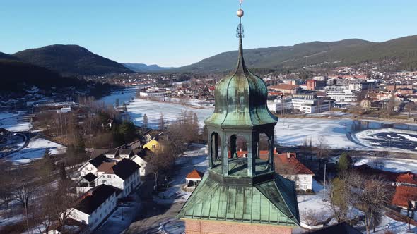 Beautiful winter aerial view of Kongsberg city with top of Church tower in foreground - Aerial slowl