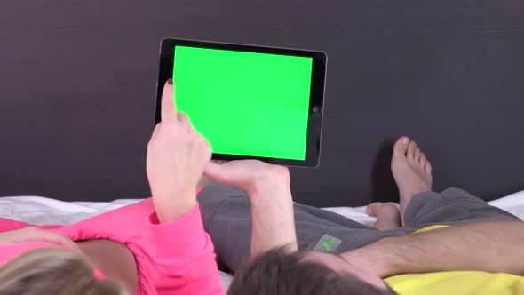 Sweet Couple on Bed Watching Something on White Tablet Gadget, Green Screen