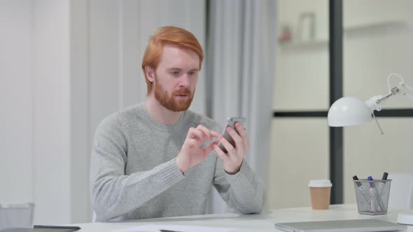 Redhead Man Celebrating While Using Smartphone