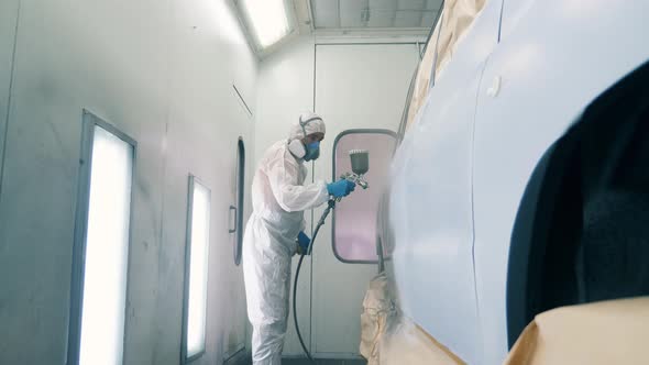 Male Worker Is Using an Airbrush To Dye the Car