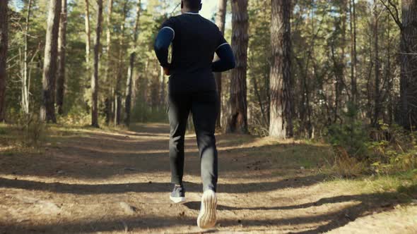 Young Fit African American Male Jogging on a Forest Road.