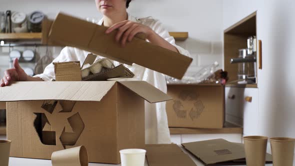 Young Caucasian Girl Folds Sorts Cardboard Paper For Reuse, Garbage Sorting For Recycling, Box