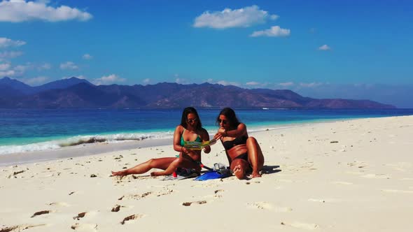 Ladies sunbathing on luxury bay beach vacation by blue ocean with white sand background of Lombok be