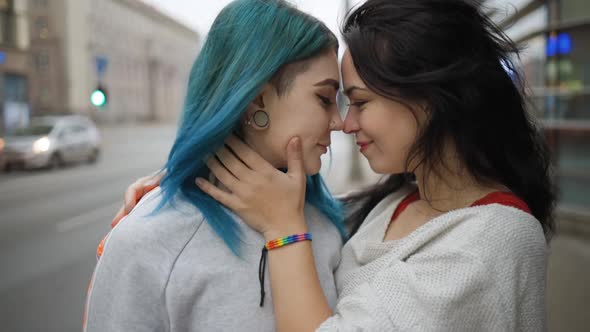 Close View Young Brunette Woman in Rainbow Bracelet Hugs Her Cute Girlfriend with Green Hair