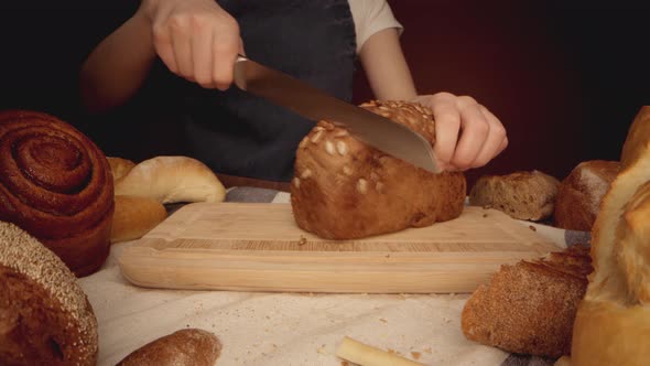 Hands of a Woman Cutting Bread Loaf on Wooden Cutting Board