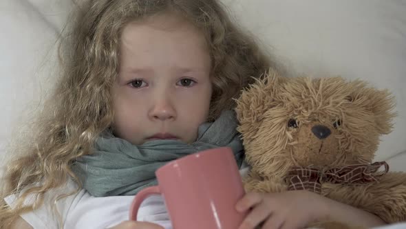 Crying Sick Girl Lying in Bed with Toy Bear