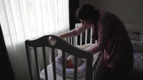 Mom Straighten the Blanket at the Sleeping in the Crib of the Newborn