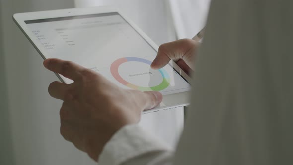 Close up Asian businessman checking report and compared with the financial information on a tablet.