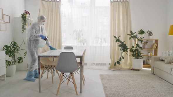 Sequence of Woman in Protective Suit Disinfecting Table at Home